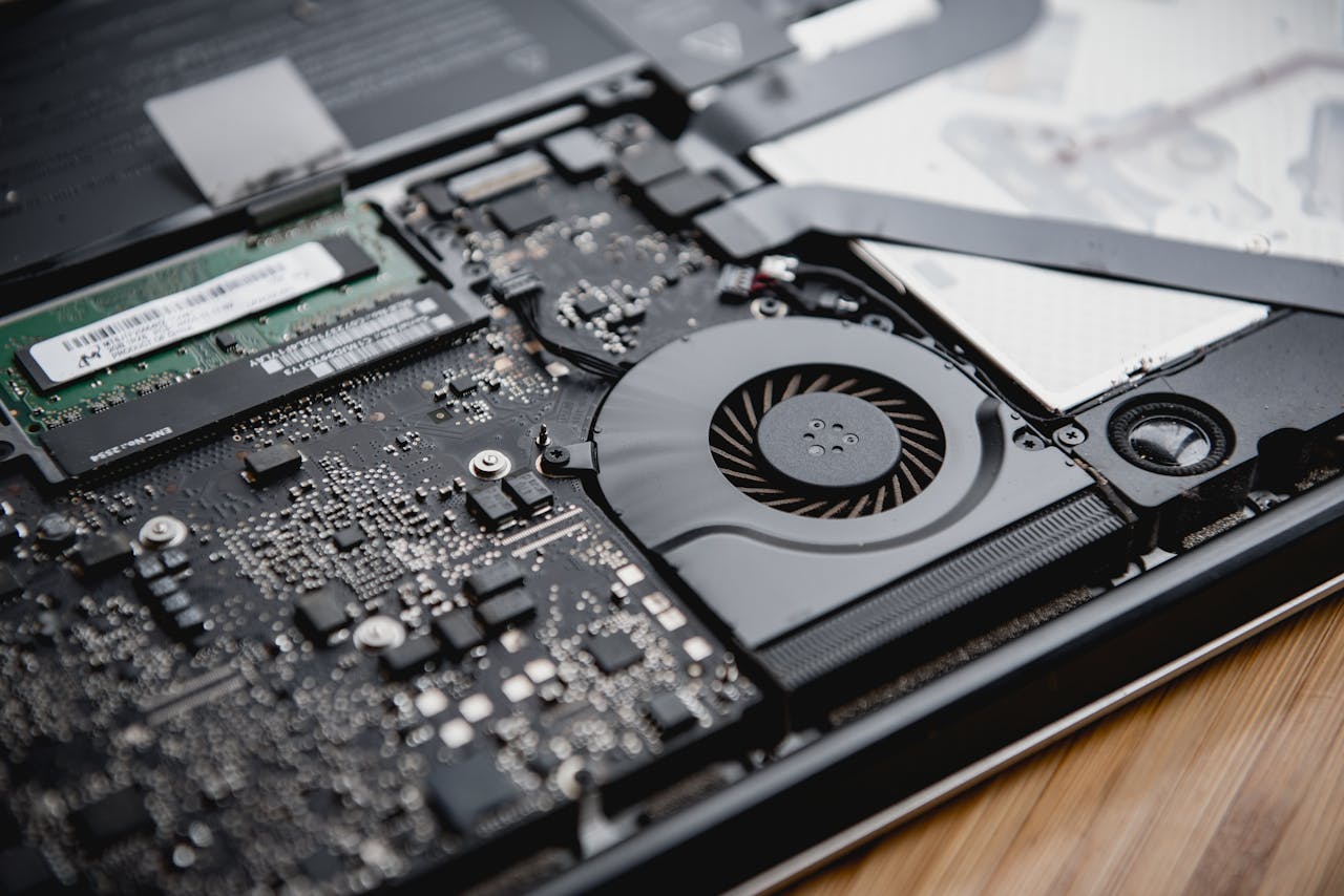 Detailed view of a laptop's internal circuitry and cooling fan showcasing technology and engineering.